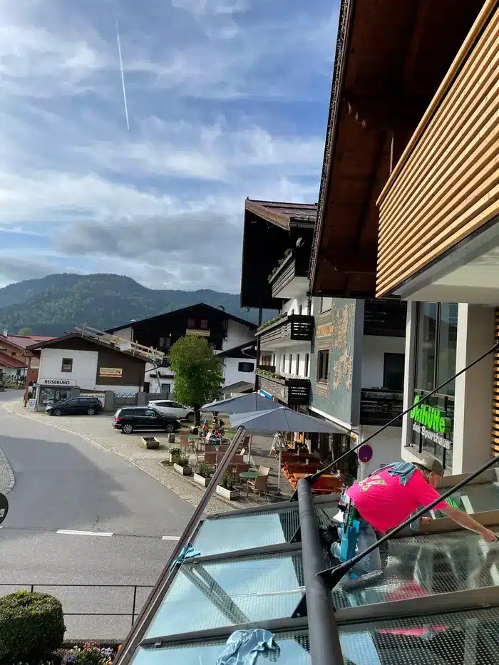 Mitarbeiter reinigt das Glasvordach der Intersport Skihütte in Reit im Winkl
