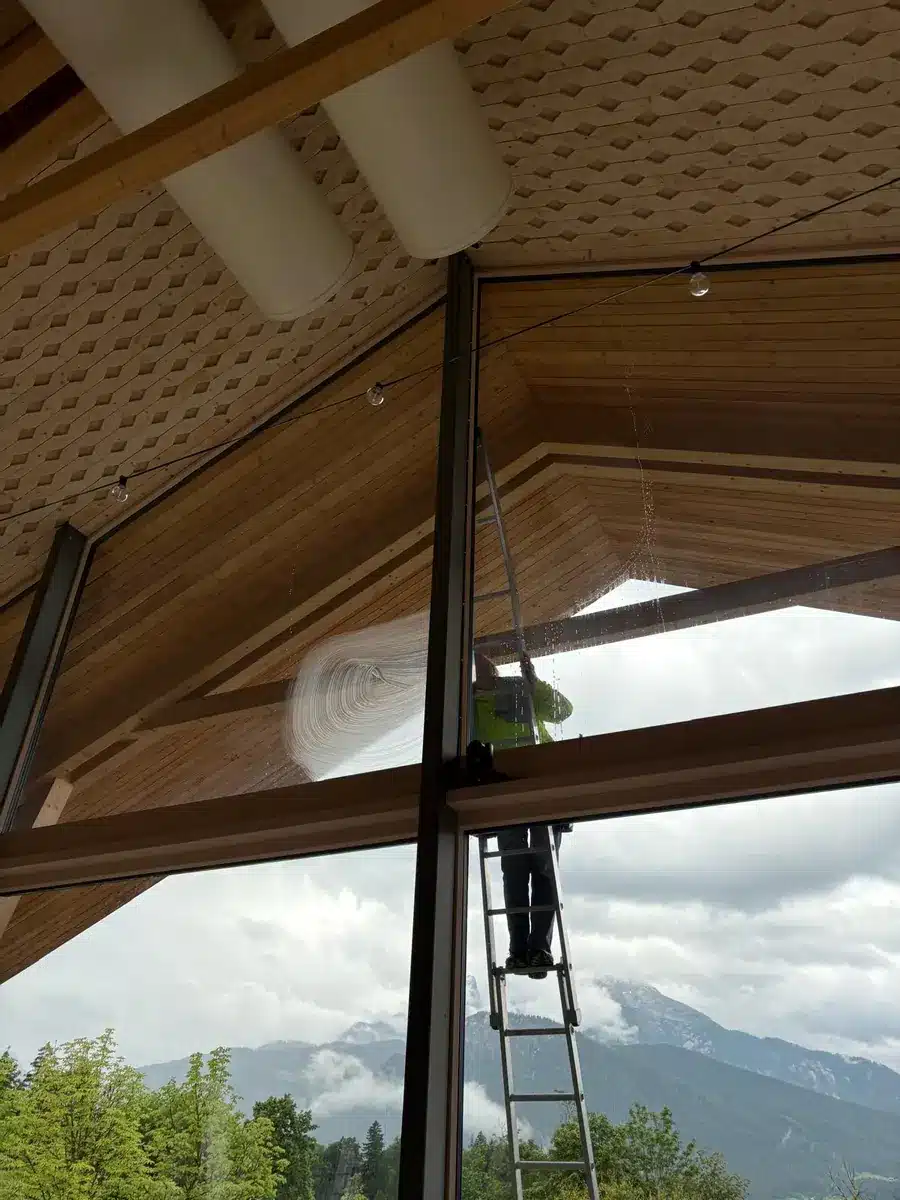 Mitarbeiter der Fix Fensterreinigung reinigt die hohe Verglasung im Kulturhof Hotel