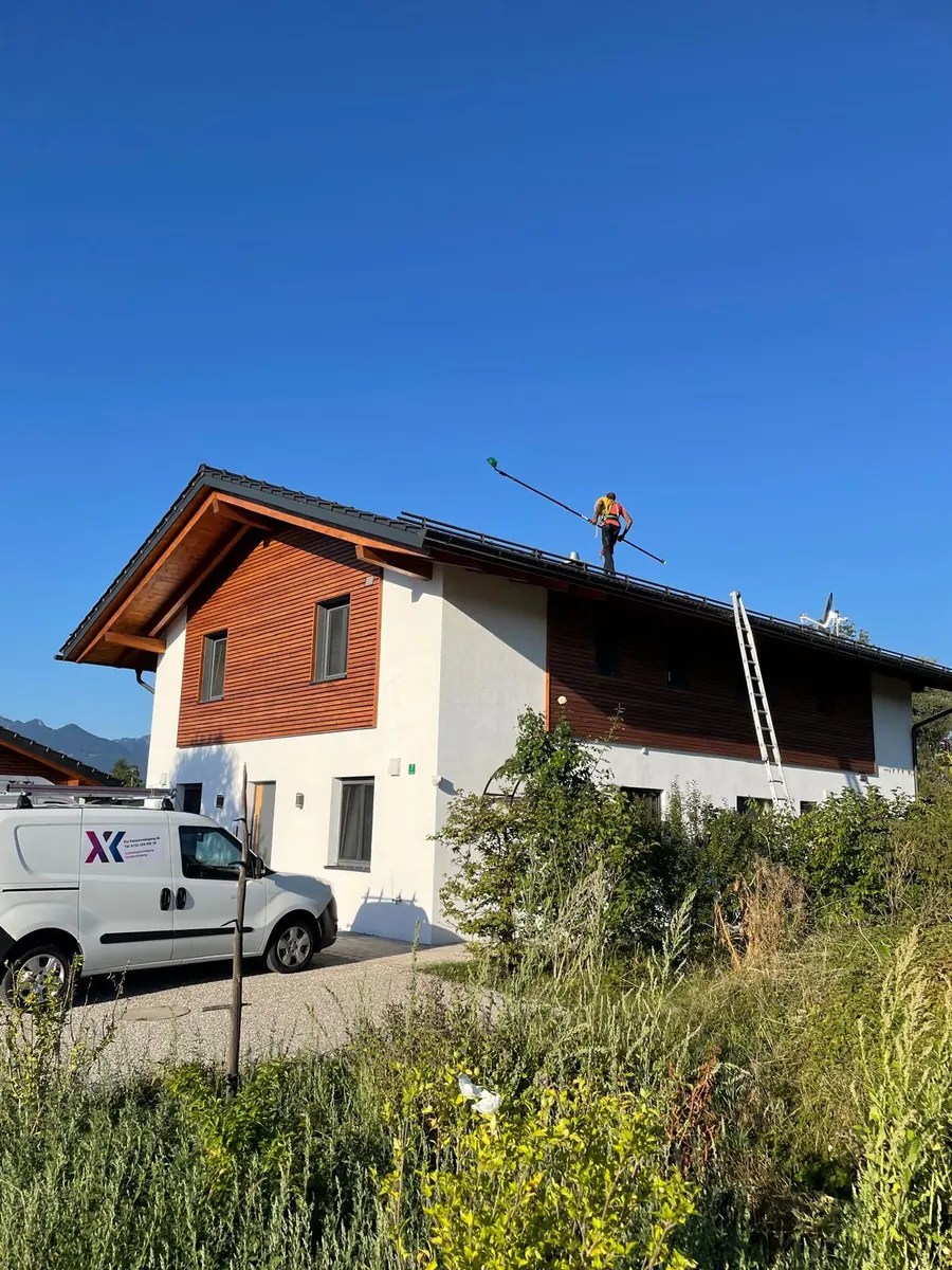 Solarreinigung in Übersee: Mitarbeiter mit Teleskopstange auf dem Dach