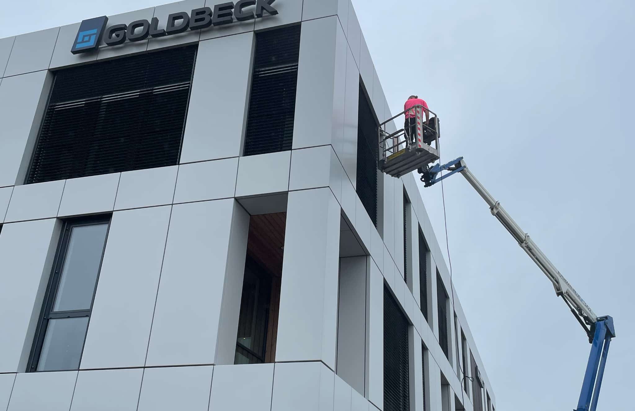 Lamellenreinigung mit einer Hubarbeitsbühne am GOLDBECK-Gebäude in Rosenheim
