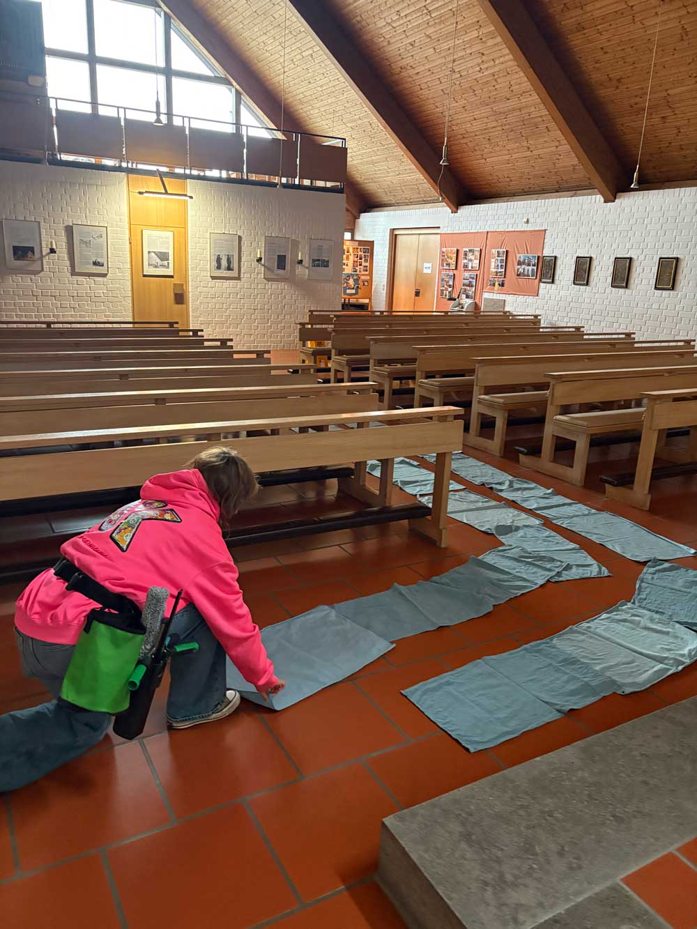 FIX-Mitarbeiterin verlegt Schutzvlies im Gang der Kirche St. Josef in Eisenärzt